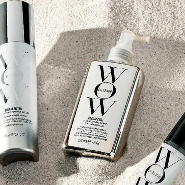 WOW hair care products resting on sand